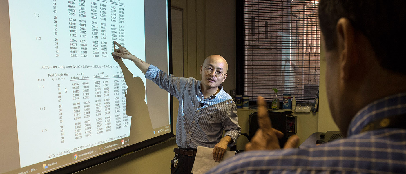 A professor points at a projected image